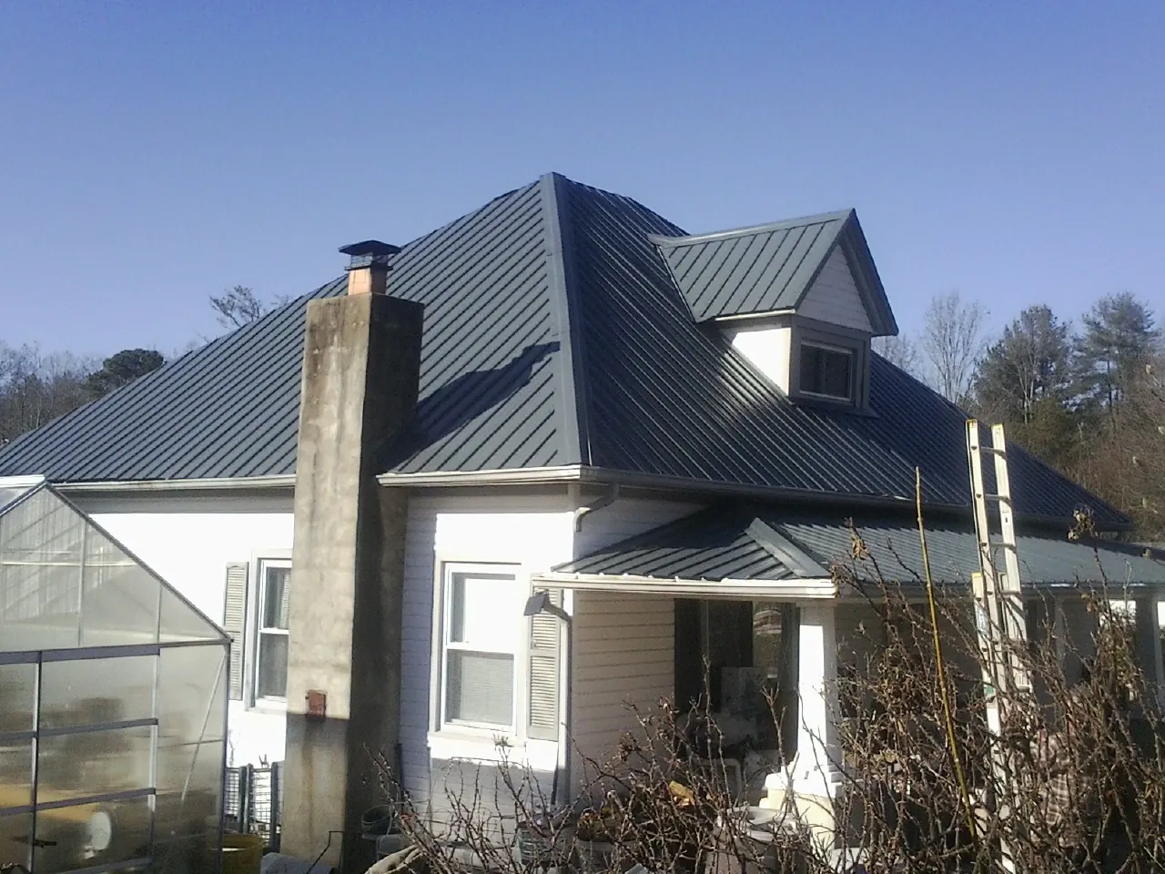Dark blue standing seam metal roof on a white farmhouse with dormer — Slate & Tile Roof Repair by Roofing Brothers in La Crescenta
