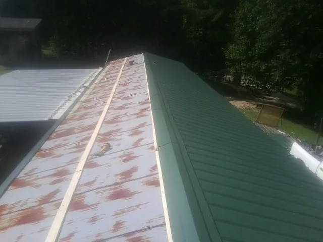 Old rusted panels beside newly installed green metal roofing — Wind Damage Roof Repair by Roofing Brothers in La Crescenta