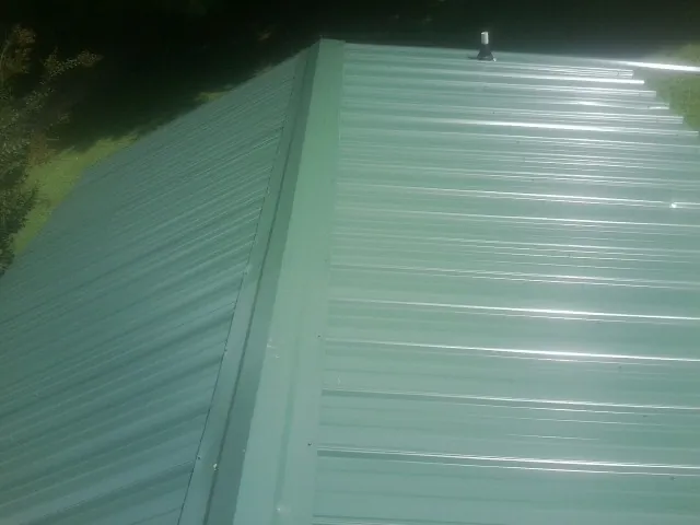 New green metal panels meeting at the ridge of a roof — Flat Roof Repair work by our crew in La Crescenta