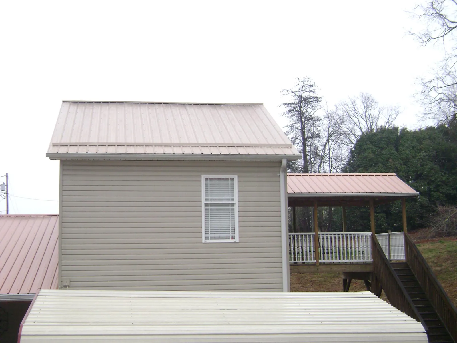 Tan metal roofs on a two story addition and attached porch, from a Roof Replacement job in La Crescenta